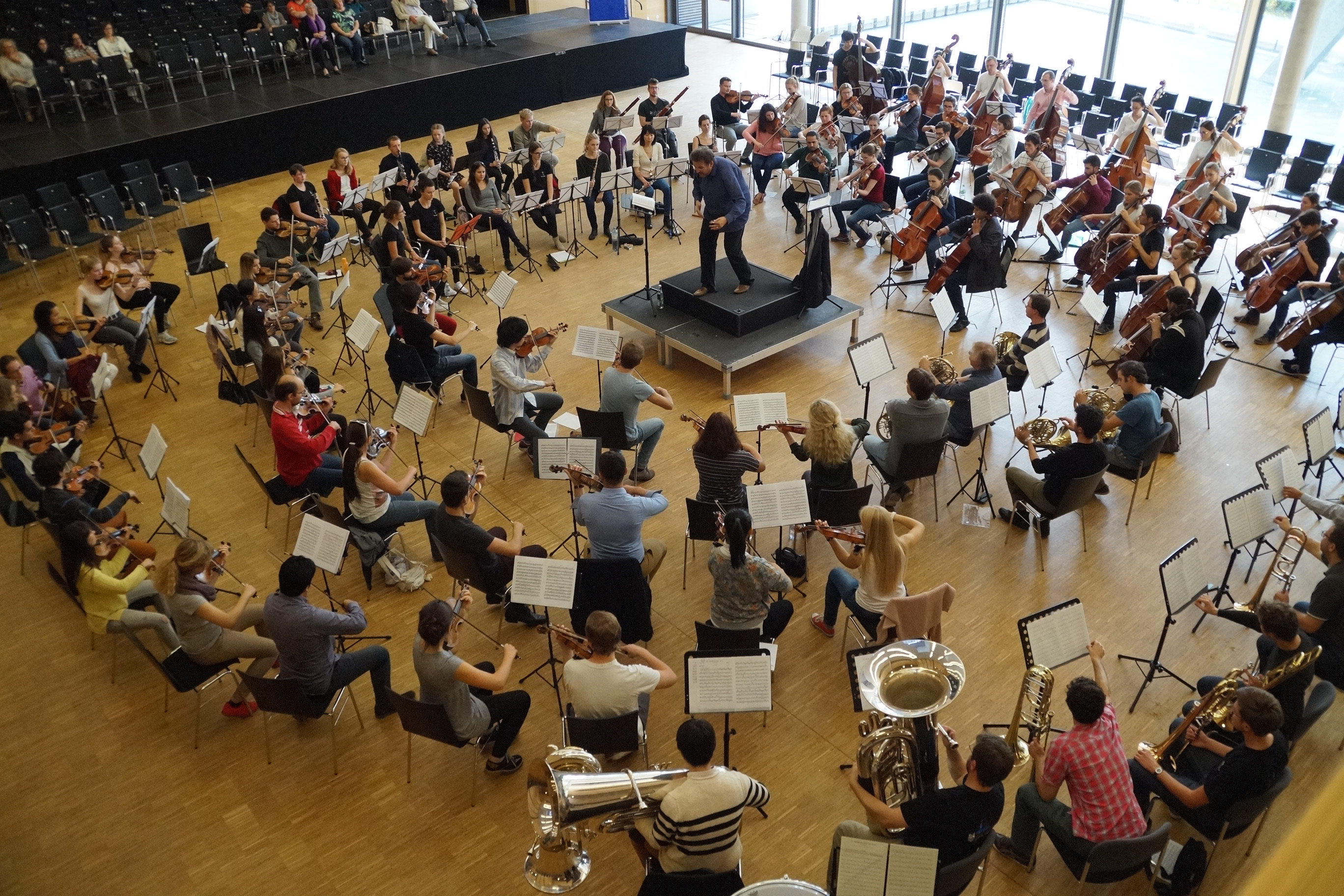 Einmaliger Anblick: Rund 130 Orchestermusiker aus 26 Ländern, konzentrisch angeordnet im Parkett der Schwarzachtalhalle...